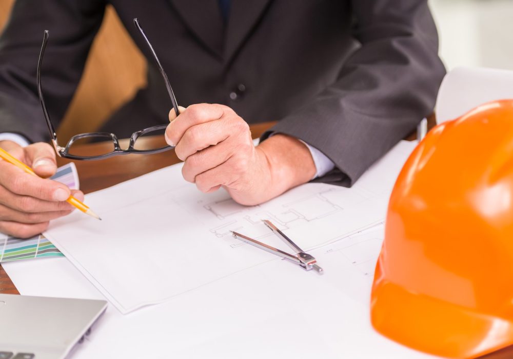 Close-up of male architect working on blueprints at the office.